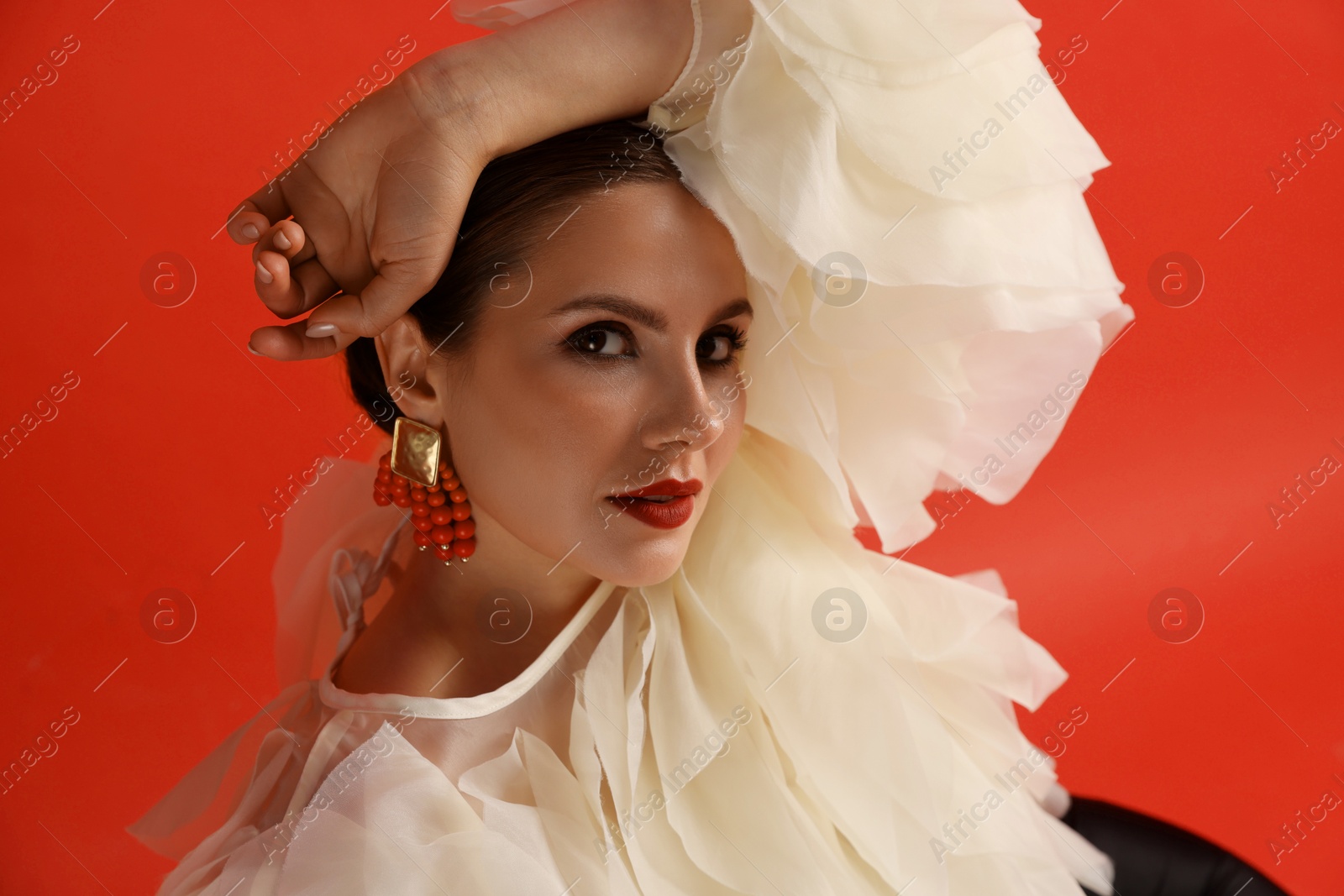 Young woman in stylish clothes on red background Photo of Young woman in stylish clothes on red background