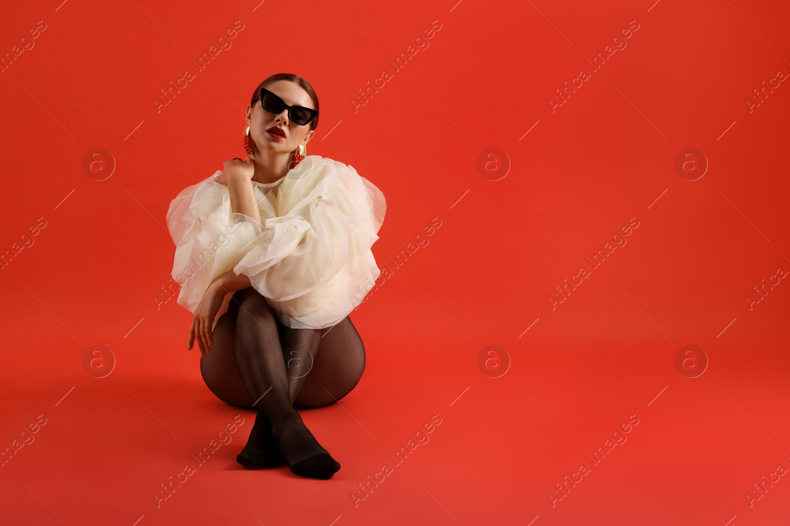 Young woman in stylish clothes on red background, space for text Photo of Young woman in stylish clothes on red background, space for text