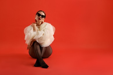 Photo of Young woman in stylish clothes on red background, space for text