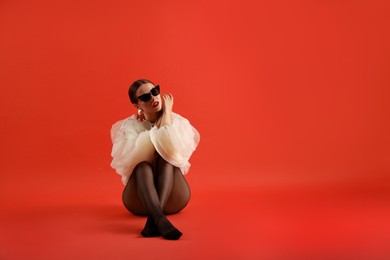 Photo of Young woman in stylish clothes on red background, space for text