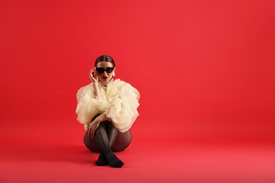 Photo of Young woman in stylish clothes on red background, space for text