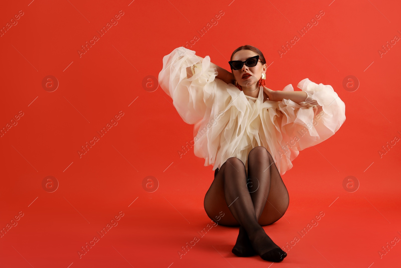 Young woman in stylish clothes on red background, space for text Photo of Young woman in stylish clothes on red background, space for text
