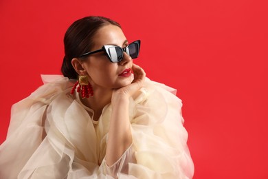 Photo of Young woman in stylish clothes on red background, space for text