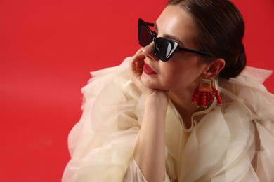 Photo of Young woman in stylish clothes on red background, space for text