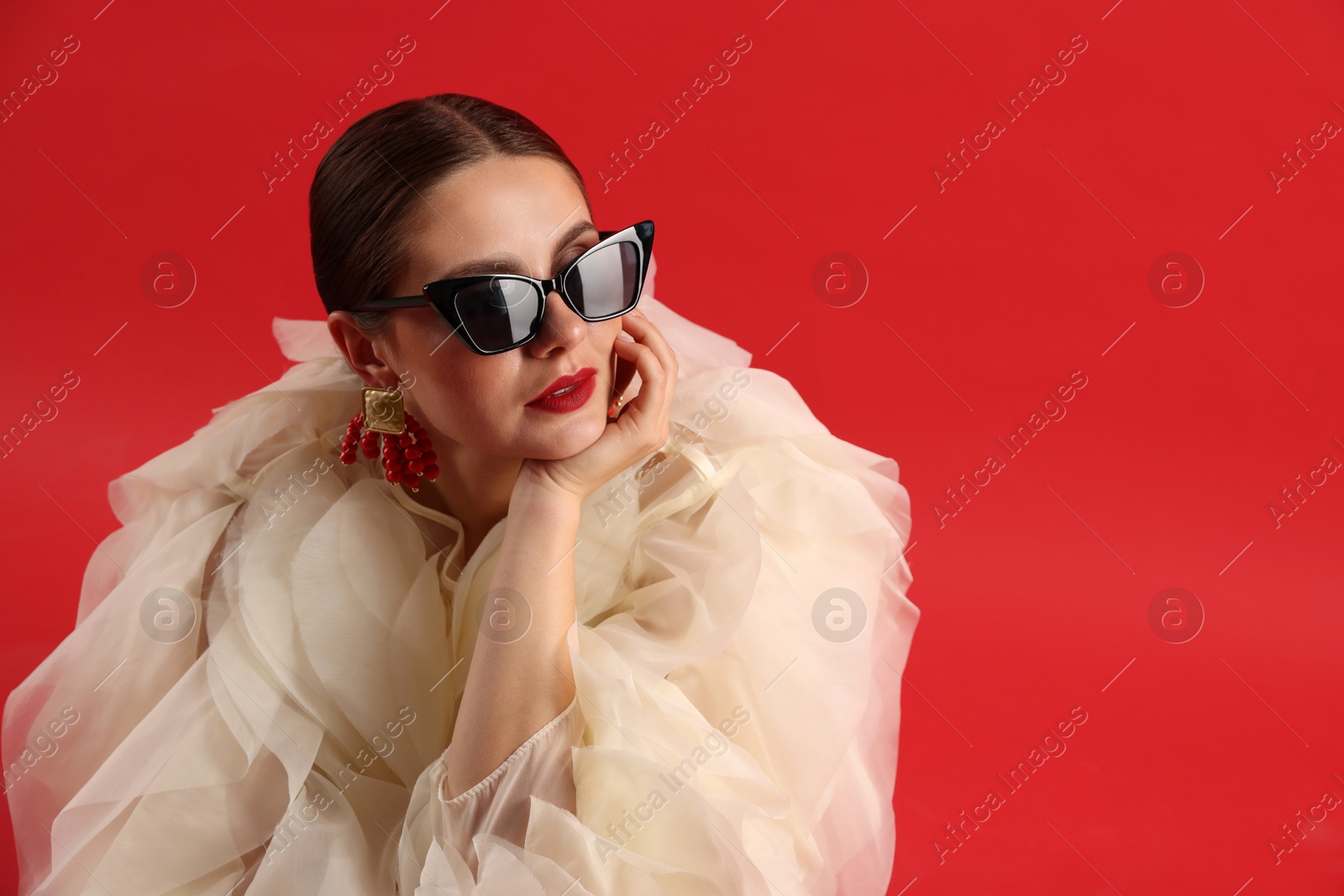 Young woman in stylish clothes on red background, space for text Photo of Young woman in stylish clothes on red background, space for text