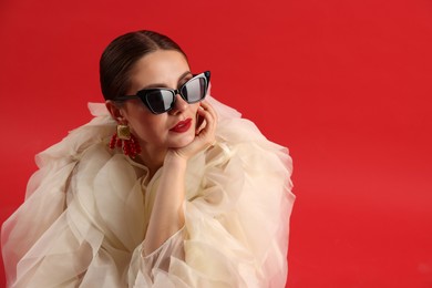 Photo of Young woman in stylish clothes on red background, space for text