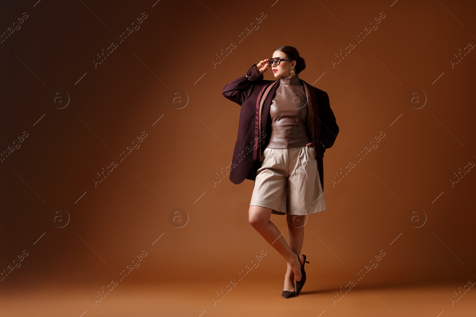 Young woman in stylish clothes on brown background, space for text Photo of Young woman in stylish clothes on brown background, space for text