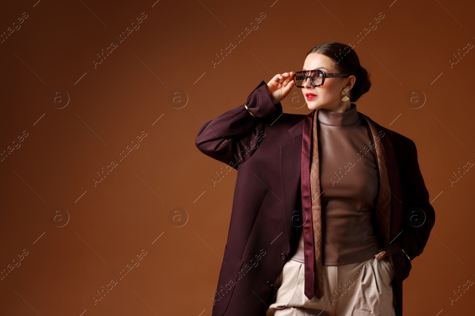 Young woman in stylish clothes on brown background, space for text Photo of Young woman in stylish clothes on brown background, space for text