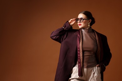 Photo of Young woman in stylish clothes on brown background, space for text