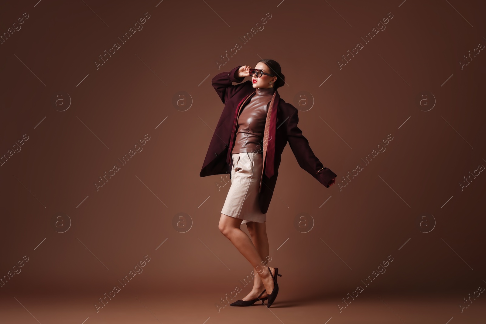 Young woman in stylish clothes on brown background Photo of Young woman in stylish clothes on brown background