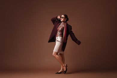 Photo of Young woman in stylish clothes on brown background