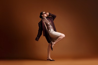 Photo of Young woman in stylish clothes on brown background