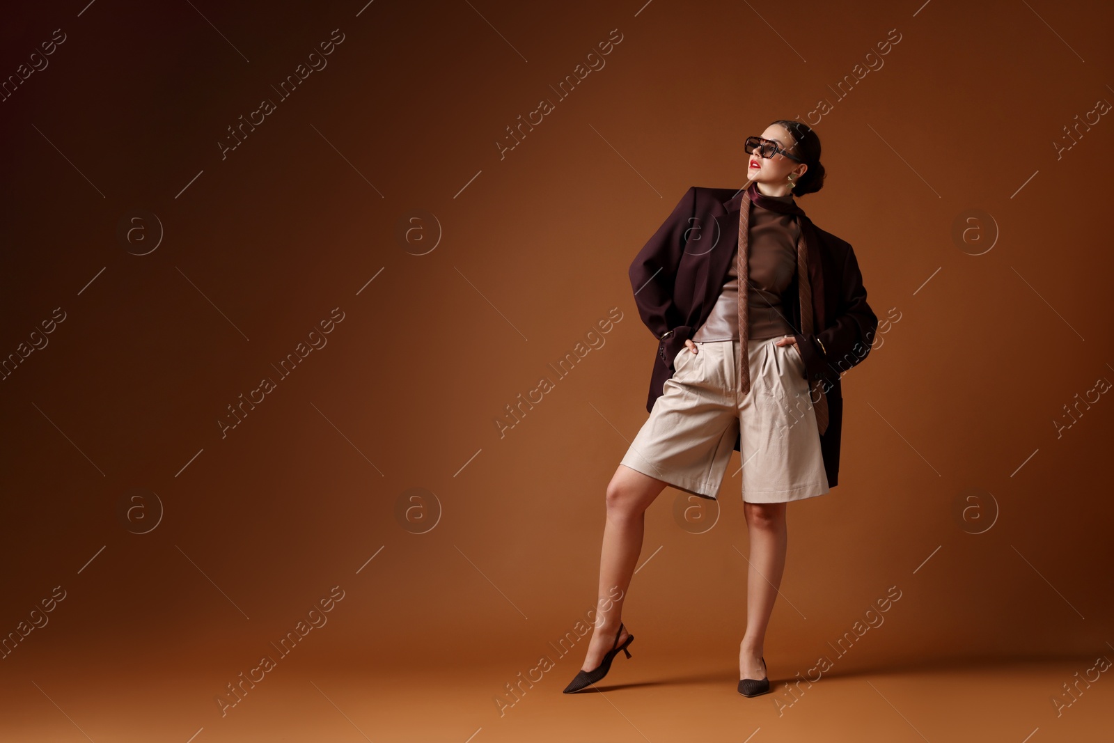 Young woman in stylish clothes on brown background, space for text Photo of Young woman in stylish clothes on brown background, space for text