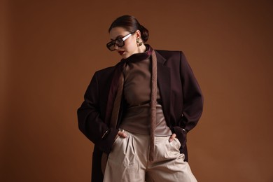 Photo of Young woman in stylish clothes on brown background