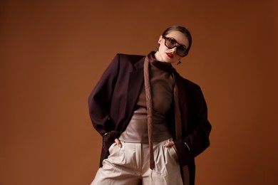 Photo of Young woman in stylish clothes on brown background