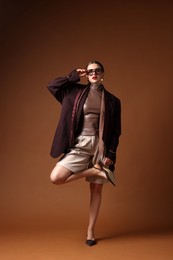 Photo of Young woman in stylish clothes on brown background