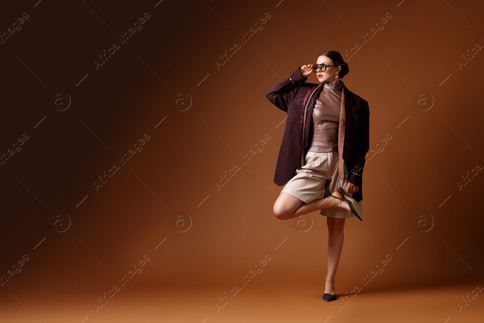 Young woman in stylish clothes on brown background, space for text Photo of Young woman in stylish clothes on brown background, space for text