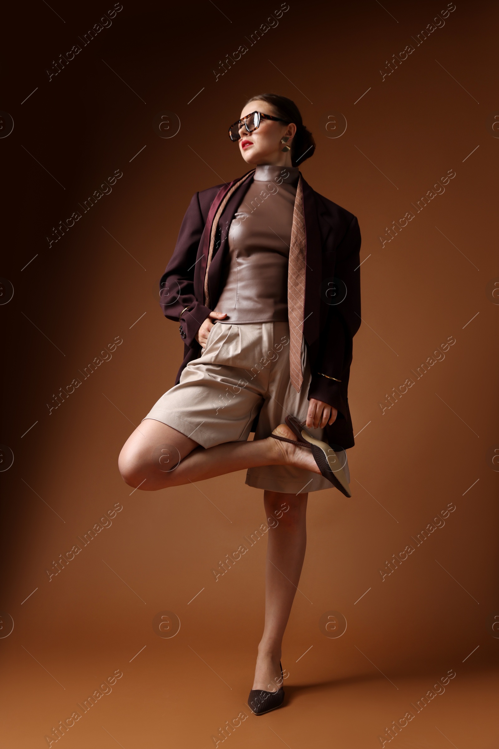Young woman in stylish clothes on brown background Photo of Young woman in stylish clothes on brown background