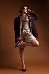Photo of Young woman in stylish clothes on brown background