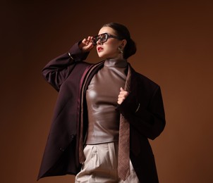 Photo of Young woman in stylish clothes on brown background