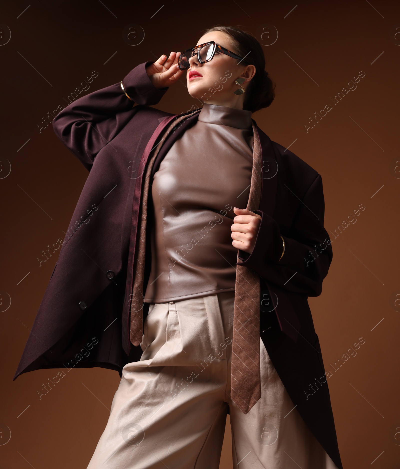 Young woman in stylish clothes on brown background Photo of Young woman in stylish clothes on brown background