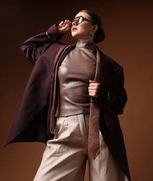 Photo of Young woman in stylish clothes on brown background