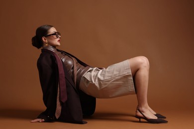 Photo of Young woman in stylish clothes on brown background
