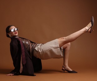Photo of Young woman in stylish clothes on brown background
