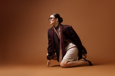 Photo of Young woman in stylish clothes on brown background