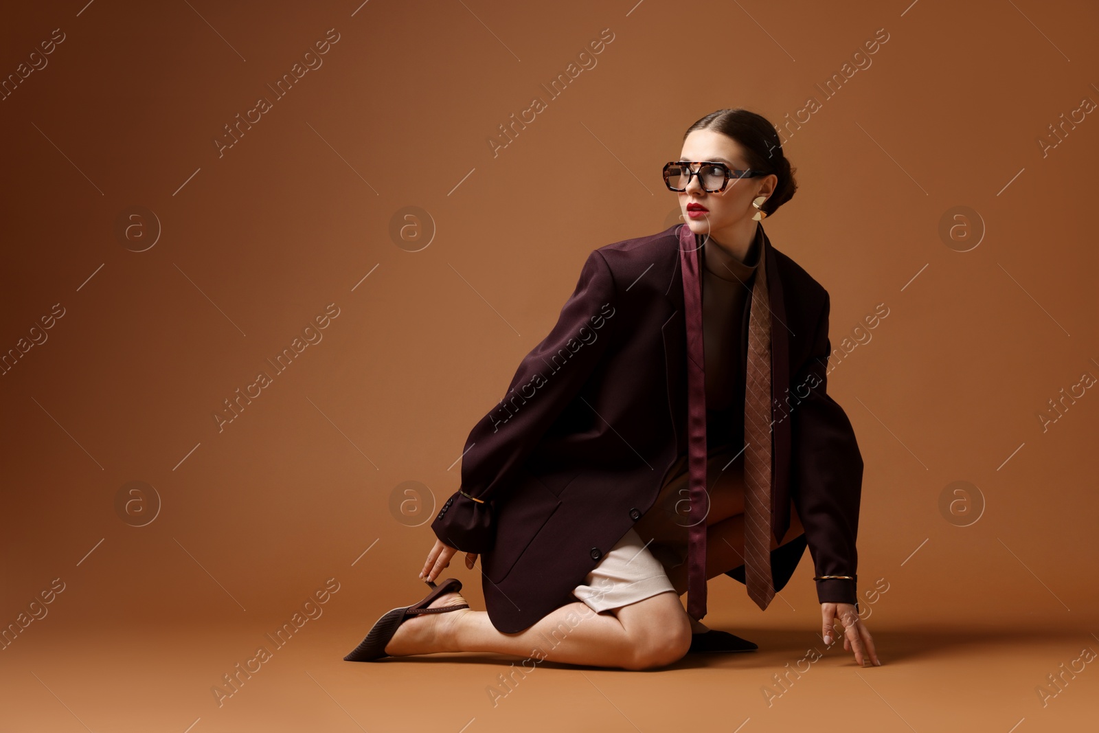 Young woman in stylish clothes on brown background Photo of Young woman in stylish clothes on brown background
