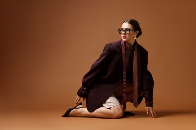Photo of Young woman in stylish clothes on brown background