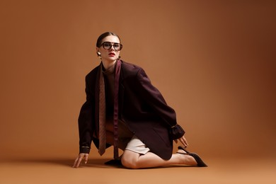 Photo of Young woman in stylish clothes on brown background