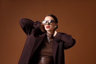 Photo of Young woman in stylish clothes on brown background