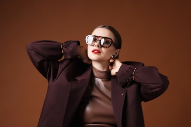 Photo of Young woman in stylish clothes on brown background