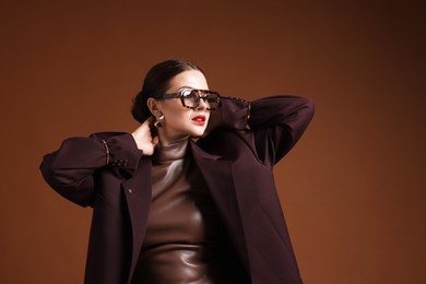 Photo of Young woman in stylish clothes on brown background