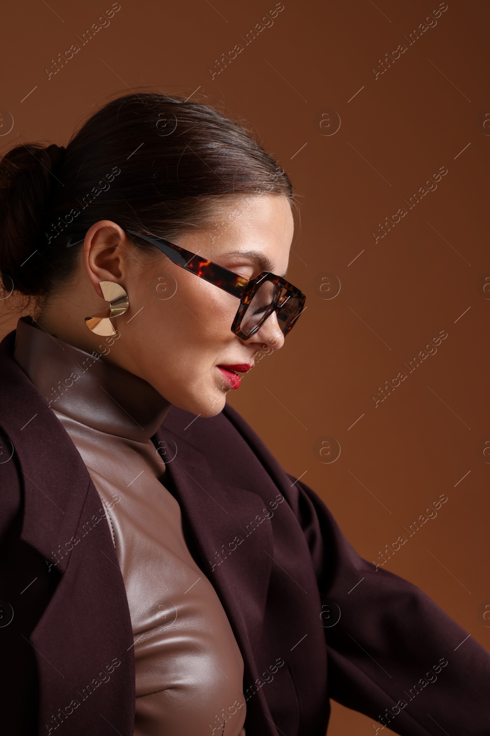 Young woman in stylish clothes on brown background Photo of Young woman in stylish clothes on brown background