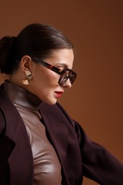 Photo of Young woman in stylish clothes on brown background