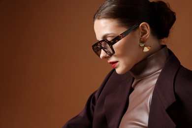 Photo of Young woman in stylish clothes on brown background, space for text