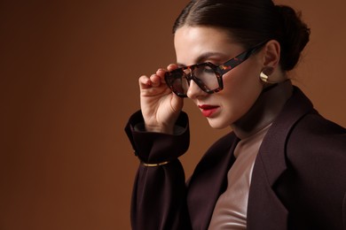 Photo of Young woman in stylish clothes on brown background, space for text