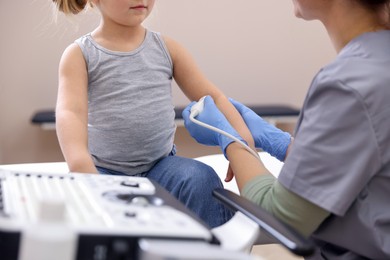 Photo of Sonographer conducting ultrasound examination of little girl's arm in clinic, closeup