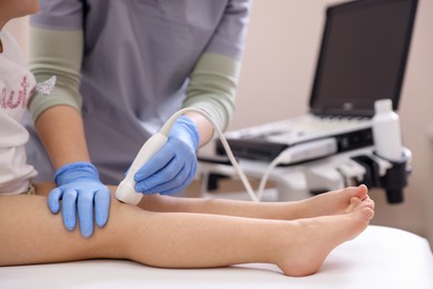 Photo of Sonographer conducting ultrasound examination of little girl's knee in clinic, closeup