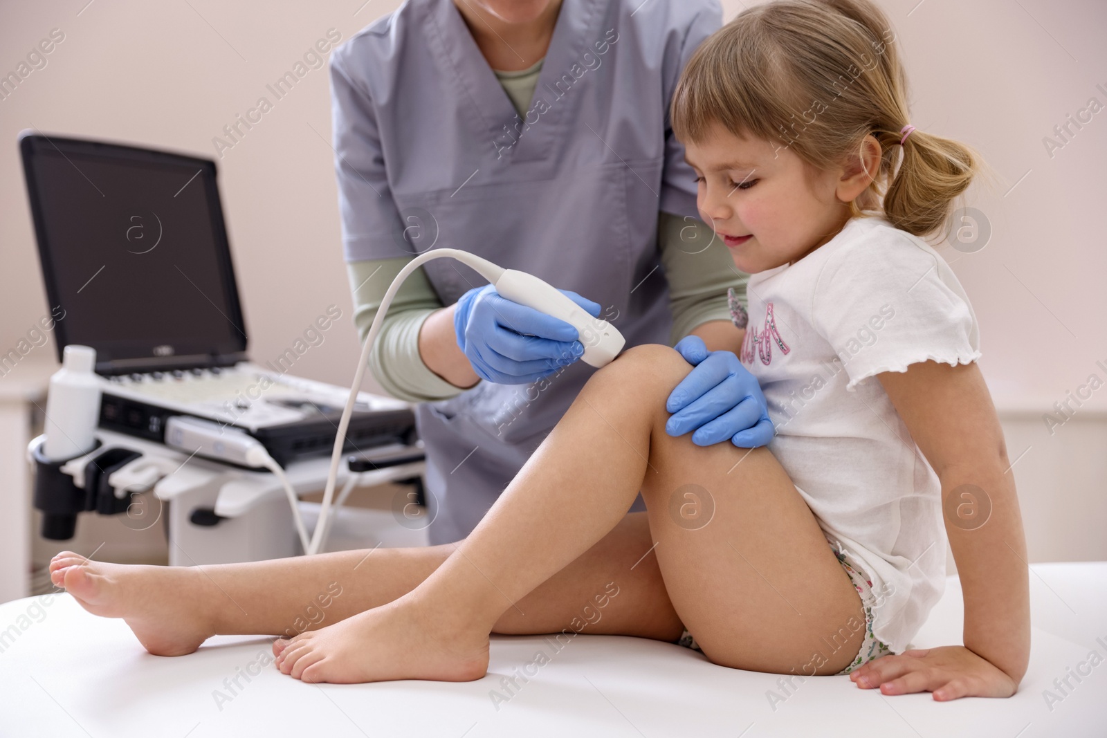 Sonographer conducting ultrasound examination of little girl's knee in clinic, closeup Photo of Sonographer conducting ultrasound examination of little girl's knee in clinic, closeup
