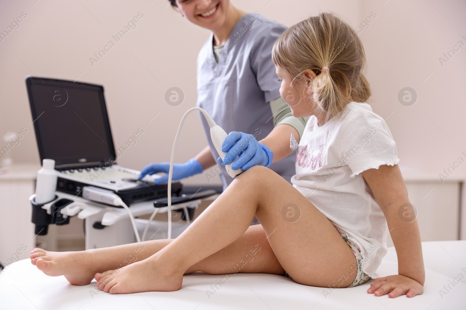 Sonographer conducting ultrasound examination of little girl's knee in clinic, closeup Photo of Sonographer conducting ultrasound examination of little girl's knee in clinic, closeup