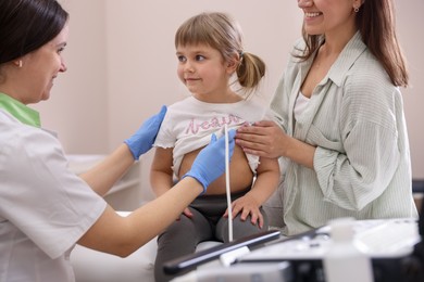 Photo of Sonographer conducting ultrasound examination of girl's heart. Mother and daughter having appointment with doctor in clinic