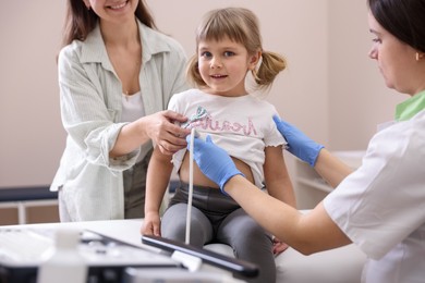 Photo of Sonographer conducting ultrasound examination of girl's heart. Mother and daughter having appointment with doctor in clinic