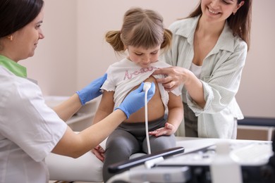 Photo of Sonographer conducting ultrasound examination of girl's heart. Mother and daughter having appointment with doctor in clinic