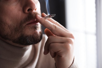 Photo of Man smoking cigarette on blurred background, closeup