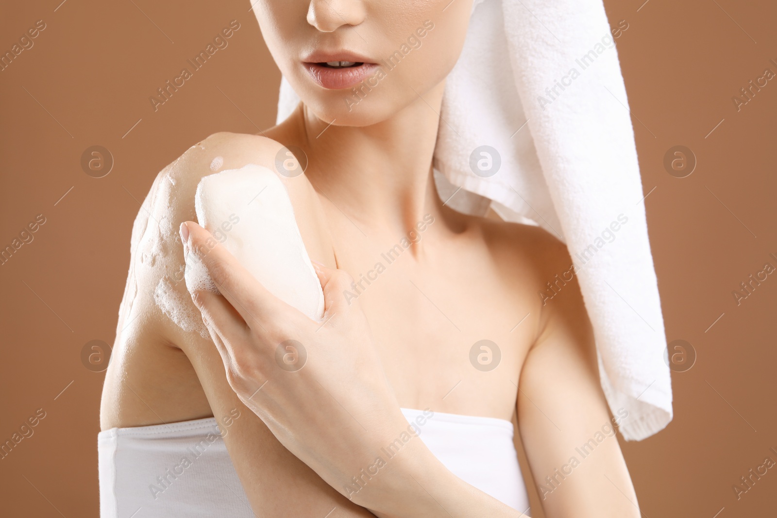Woman washing body with soap bar on brown background, closeup Photo of Woman washing body with soap bar on brown background, closeup