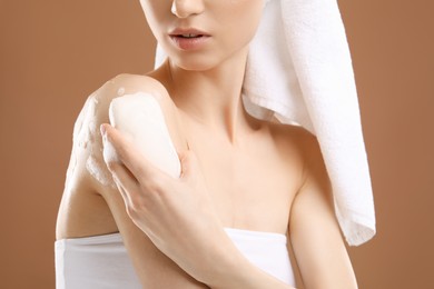 Photo of Woman washing body with soap bar on brown background, closeup