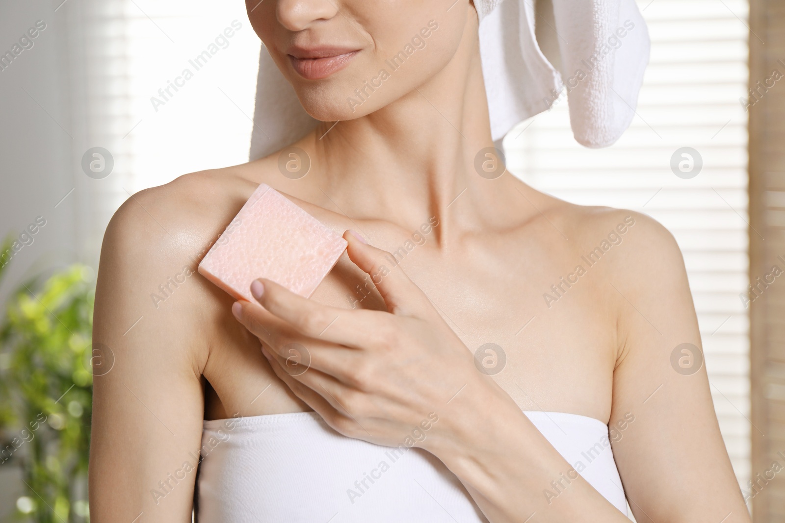 Woman with pink soap bar indoors, closeup Photo of Woman with pink soap bar indoors, closeup